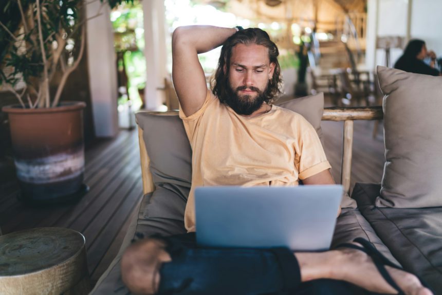 Caucasian freelancer browsing web design on modern laptop computer - typing content text at terrace